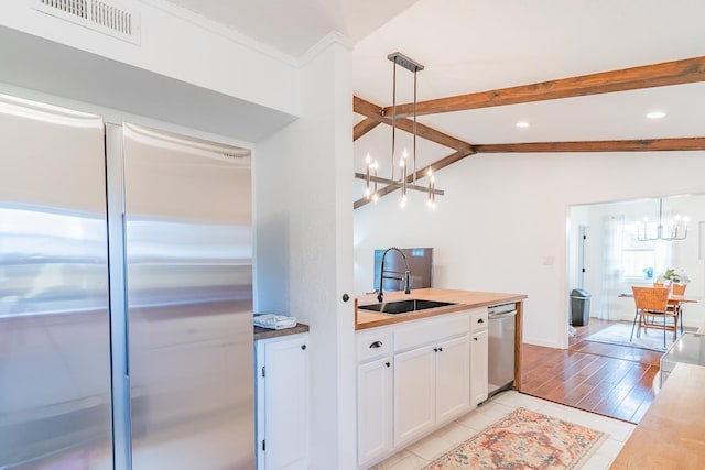 kitchen with sink, stainless steel appliances, white cabinets, decorative light fixtures, and a chandelier