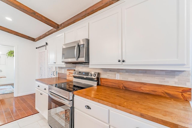 kitchen featuring white cabinetry, stainless steel appliances, a barn door, and tasteful backsplash