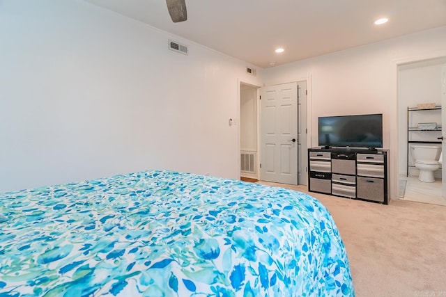 carpeted bedroom with ensuite bath and ceiling fan