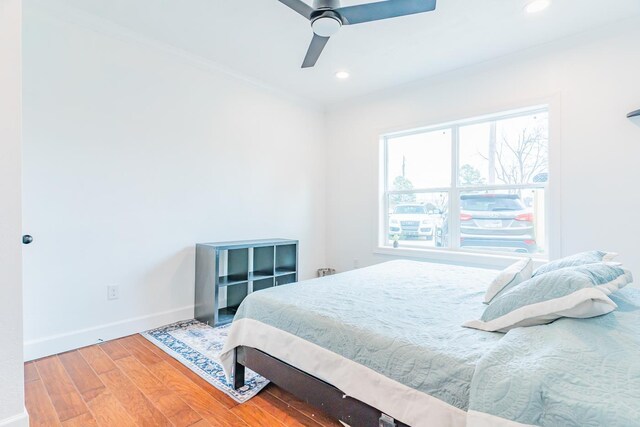 bedroom featuring wood-type flooring, ornamental molding, and ceiling fan