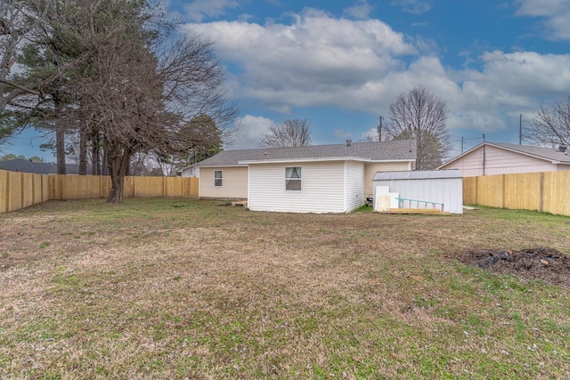 rear view of house featuring a lawn and a storage unit