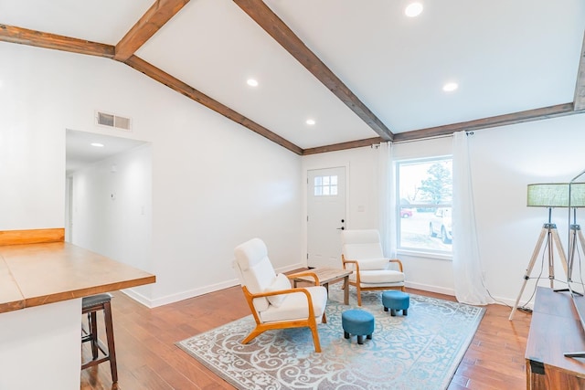 living area featuring light hardwood / wood-style floors and lofted ceiling with beams