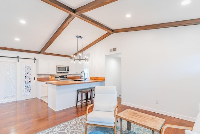 kitchen with sink, a kitchen breakfast bar, hanging light fixtures, kitchen peninsula, and stainless steel appliances