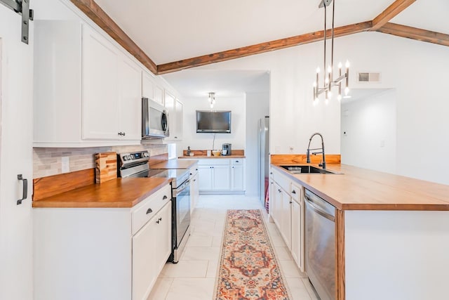 kitchen with appliances with stainless steel finishes, pendant lighting, sink, white cabinets, and backsplash