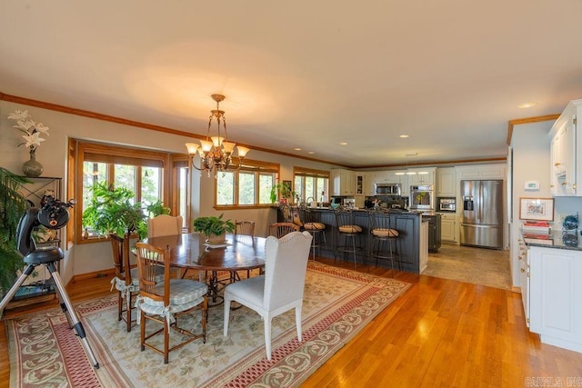 dining area with ornamental molding, light hardwood / wood-style flooring, and a notable chandelier