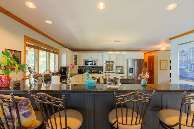 kitchen featuring ornamental molding, stainless steel appliances, kitchen peninsula, and white cabinets