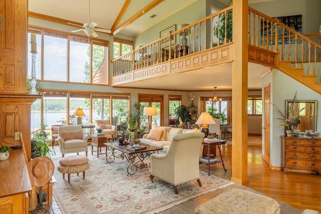 living room with hardwood / wood-style flooring, ornamental molding, a high ceiling, and ceiling fan with notable chandelier