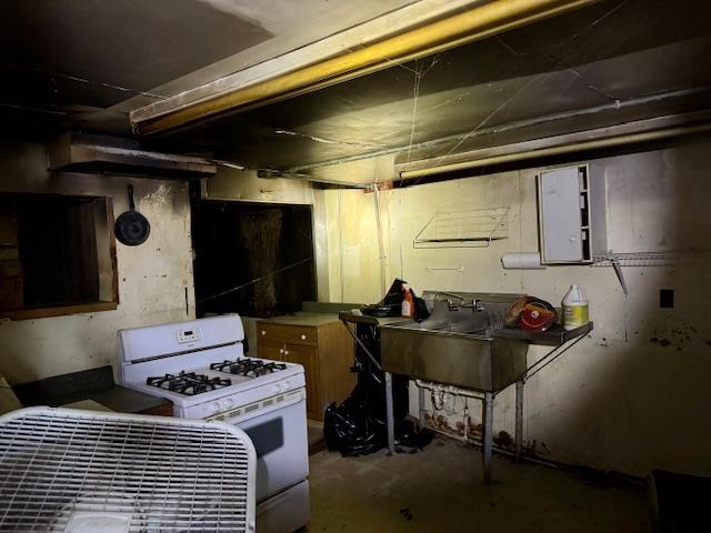 kitchen with white gas range, sink, and concrete floors