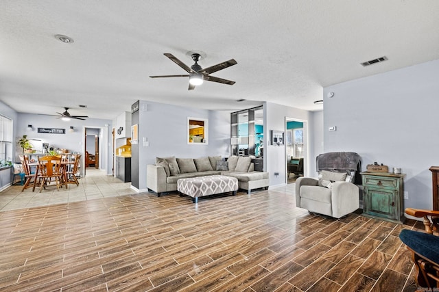 living room with ceiling fan and a textured ceiling