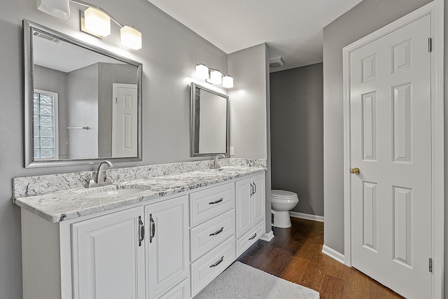 bathroom featuring wood-type flooring, vanity, and toilet