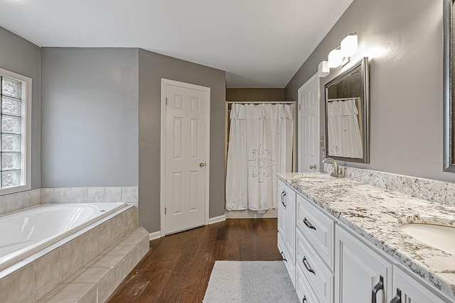 bathroom featuring a relaxing tiled tub, vanity, and hardwood / wood-style floors