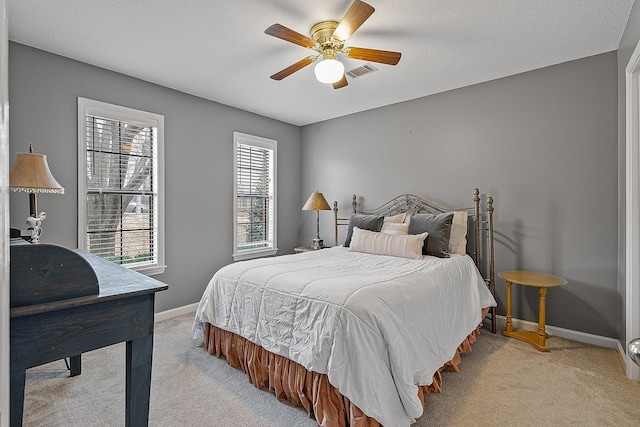 bedroom with ceiling fan, light colored carpet, and a textured ceiling