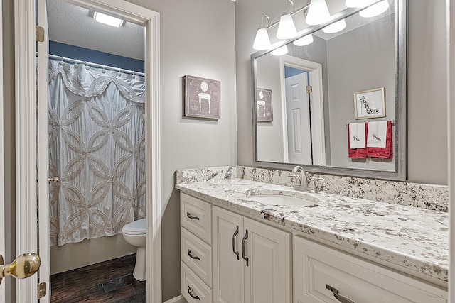 bathroom with vanity, wood-type flooring, a textured ceiling, and toilet