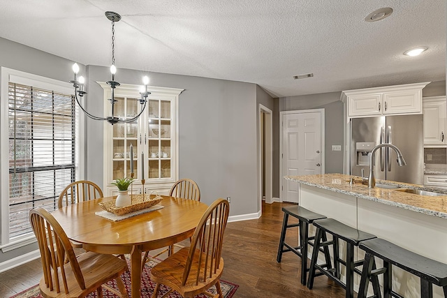 dining area featuring an inviting chandelier, dark hardwood / wood-style flooring, sink, and a textured ceiling