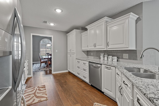 kitchen featuring dark wood-type flooring, sink, light stone counters, appliances with stainless steel finishes, and white cabinets