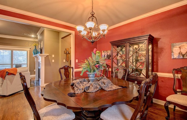 dining room with crown molding, wood-type flooring, and a chandelier