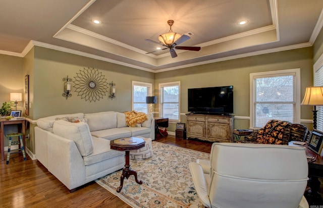 living room with wood-type flooring, ornamental molding, ceiling fan, and a tray ceiling