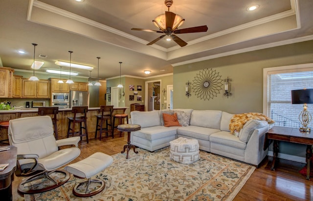 living room featuring crown molding, dark hardwood / wood-style floors, a raised ceiling, and ceiling fan