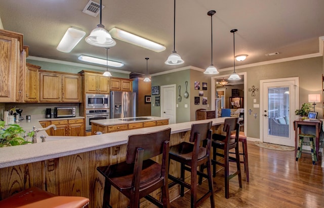 kitchen featuring decorative light fixtures, dark hardwood / wood-style floors, a center island, and appliances with stainless steel finishes