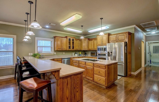 kitchen with decorative light fixtures, a kitchen bar, kitchen peninsula, stainless steel appliances, and dark wood-type flooring