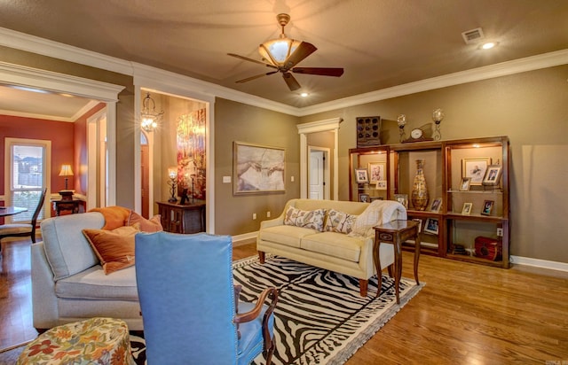 living room with wood-type flooring, ornamental molding, and ceiling fan