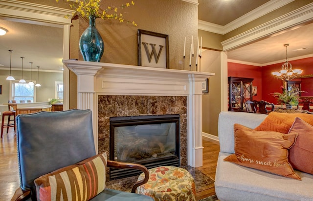 sitting room featuring wood-type flooring, ornamental molding, a premium fireplace, and a chandelier