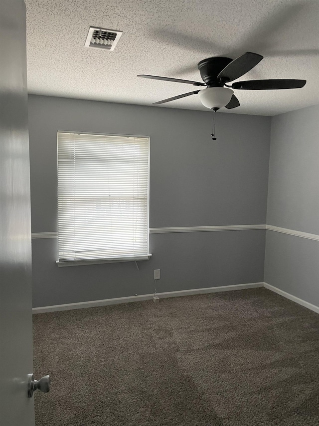 spare room featuring ceiling fan, a textured ceiling, and dark colored carpet