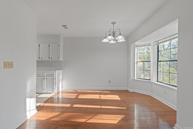 unfurnished dining area featuring light wood-type flooring and a chandelier