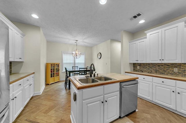 kitchen with pendant lighting, white cabinetry, sink, stainless steel appliances, and a center island with sink