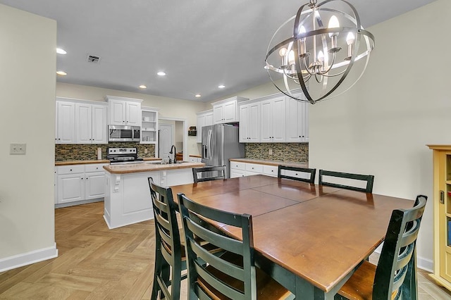 dining area featuring an inviting chandelier, sink, and light parquet floors