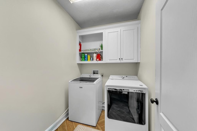 washroom with cabinets, washing machine and dryer, and a textured ceiling