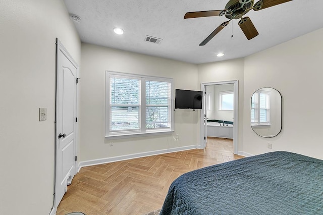 bedroom featuring light parquet floors, ensuite bathroom, ceiling fan, and a textured ceiling