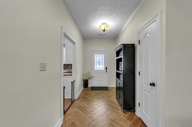 doorway with light parquet flooring and a textured ceiling