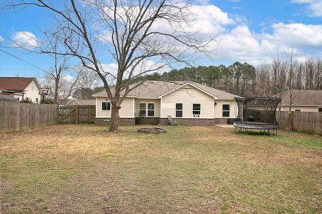 back of property with a trampoline and a yard