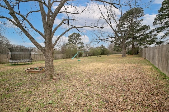 view of yard featuring a trampoline and a playground