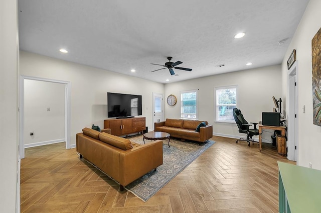 living room featuring ceiling fan, a textured ceiling, and light parquet flooring