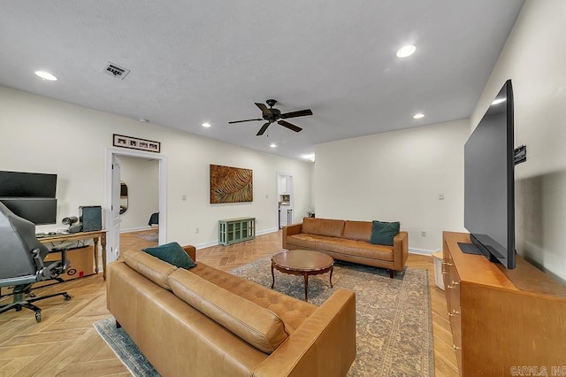 living room with light parquet floors, ceiling fan, and a textured ceiling