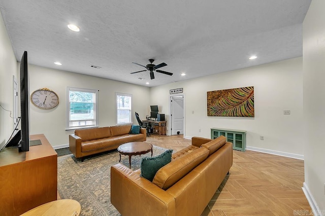 living room with ceiling fan, light parquet flooring, and a textured ceiling