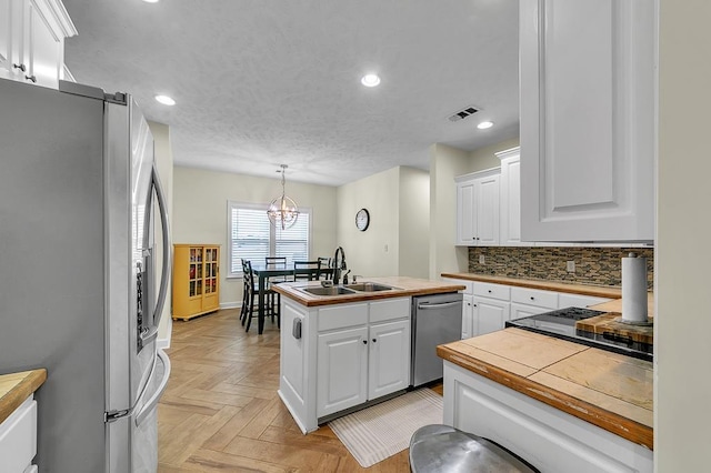 kitchen featuring pendant lighting, sink, white cabinets, and appliances with stainless steel finishes