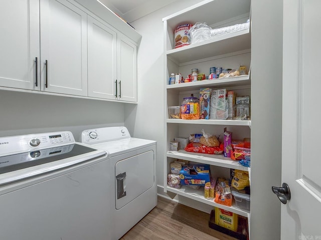 washroom featuring washer and dryer, cabinets, and light wood-type flooring