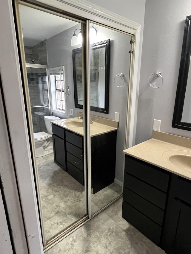 bathroom with vanity, a shower with door, and toilet