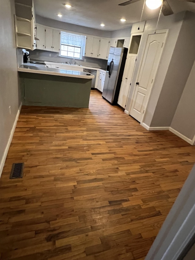 kitchen with ceiling fan, appliances with stainless steel finishes, white cabinets, dark hardwood / wood-style flooring, and kitchen peninsula