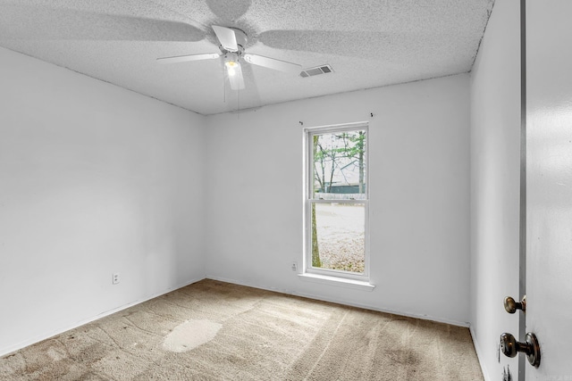 carpeted spare room with ceiling fan, visible vents, and a textured ceiling