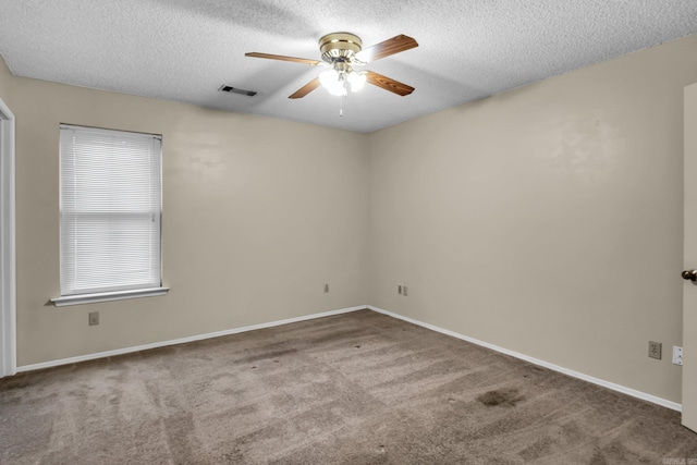 carpeted empty room with a ceiling fan, visible vents, a textured ceiling, and baseboards