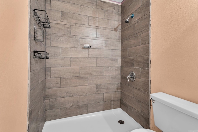 bathroom featuring tiled shower and toilet