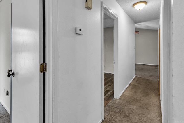 hall featuring carpet floors, a textured ceiling, and baseboards