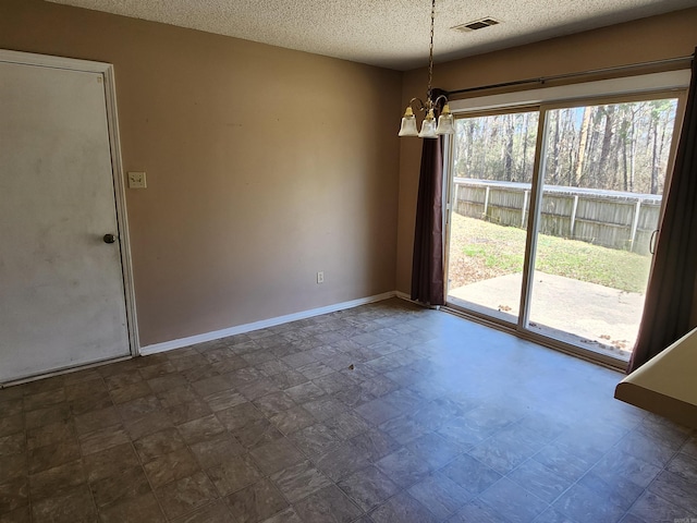 spare room with baseboards, a healthy amount of sunlight, visible vents, and an inviting chandelier