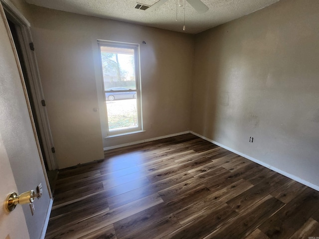 spare room with a ceiling fan, a textured ceiling, baseboards, and dark wood-type flooring