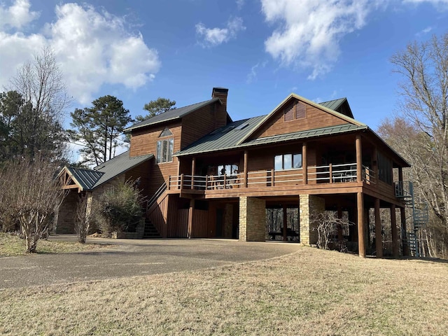 rear view of property featuring a wooden deck and a lawn