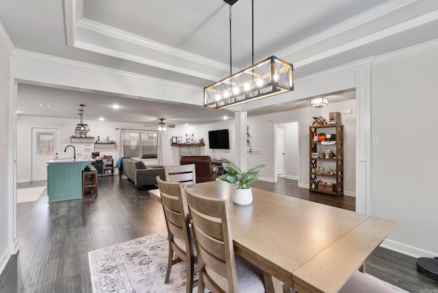 dining room featuring crown molding, dark wood-type flooring, ceiling fan, and a tray ceiling